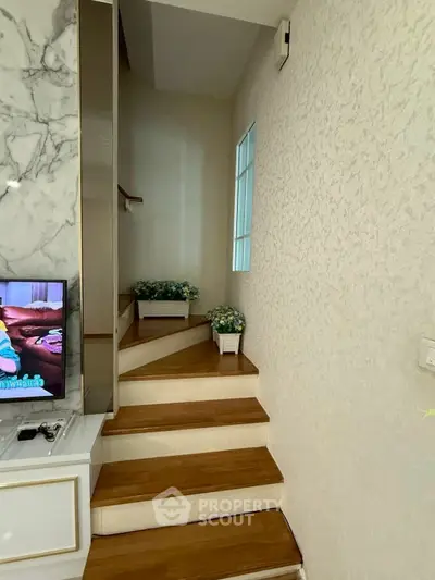 Charming interior staircase with wooden steps and decorative plants, leading to a cozy upper level.