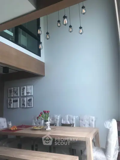 Modern dining area with high ceiling and stylish lighting in a contemporary home.