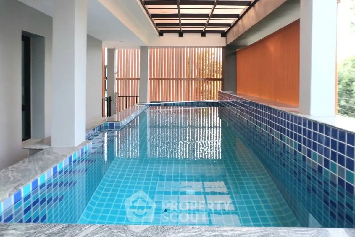 Luxurious indoor pool with modern design and blue tile accents, perfect for relaxation and leisure.
