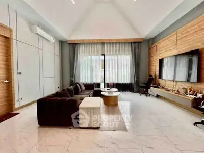 Spacious modern living room with high ceiling and large window, featuring elegant decor and comfortable seating.