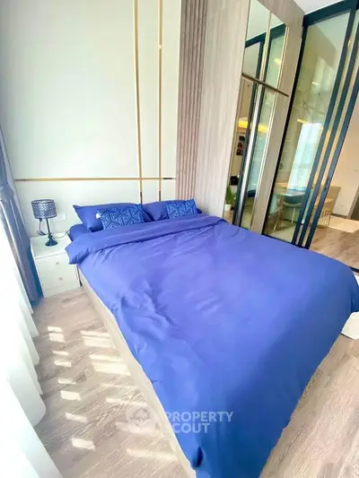 Luxurious bedroom with elegant blue bedding and mirrored wardrobe in modern apartment.