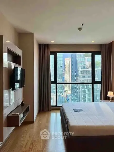 Modern bedroom with city view and sleek furnishings in high-rise apartment.