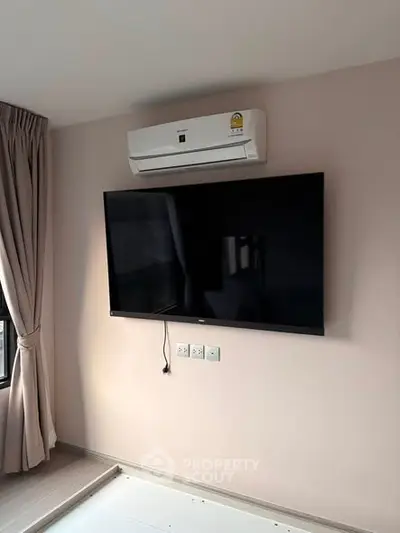 Modern living room with wall-mounted TV and air conditioning unit, perfect for comfortable living.