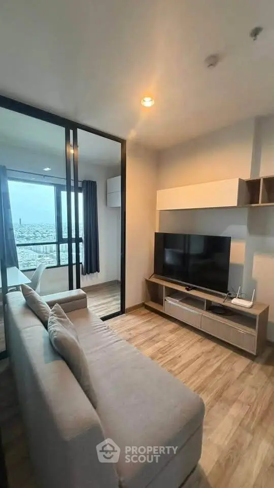 Modern living room with sleek design and city view, featuring a comfortable sofa and large TV.