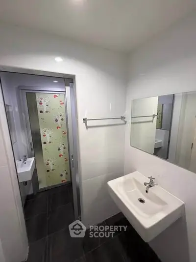 Modern bathroom with sleek white sink and large mirror, featuring a stylish sliding door with decorative glass.