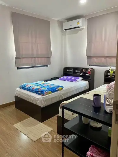 Cozy bedroom with twin beds, air conditioning, and modern decor, perfect for comfortable living.