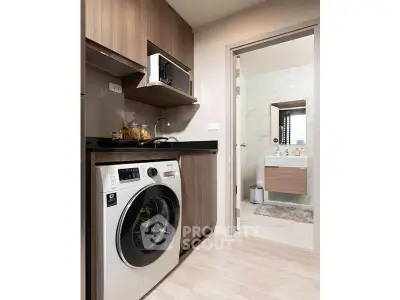 Modern kitchen with washing machine and view into stylish bathroom