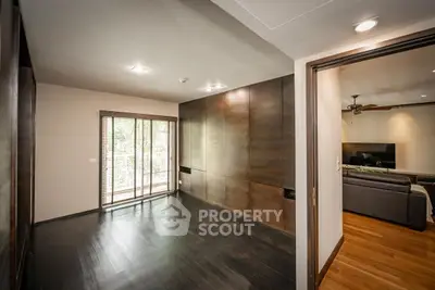 Spacious modern living room with wooden flooring and large windows opening to a balcony.