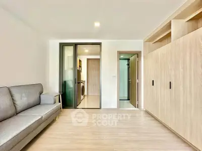 Modern living room with sleek design and built-in storage, adjacent to a compact kitchen area.