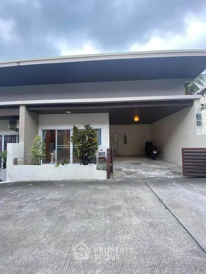 Modern single-story house with covered parking and lush greenery.