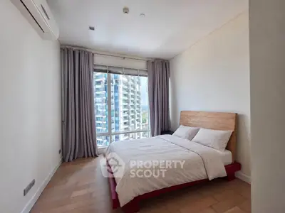 Spacious bedroom with large window offering stunning city views in modern apartment.