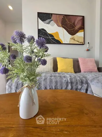 Stylish living room with cozy sofa, vibrant cushions, and elegant floral decor on wooden table.