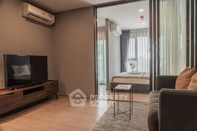 Modern living room with open view to a cozy bedroom, featuring stylish furniture and natural light.