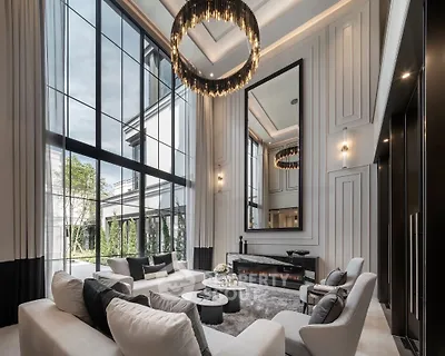 Luxurious living room with high ceilings, elegant chandeliers, and large windows offering garden views.