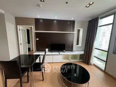 Modern living room with sleek furniture and large windows offering city views.