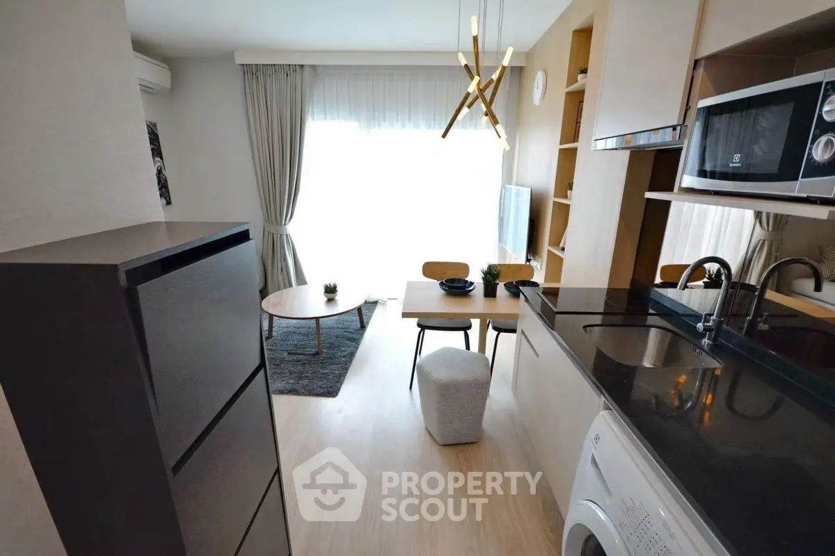 Modern open-plan living room with kitchen, featuring sleek appliances and stylish decor.
