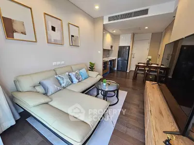 Modern living room with stylish decor and open kitchen layout, featuring a cozy sofa and elegant furnishings.