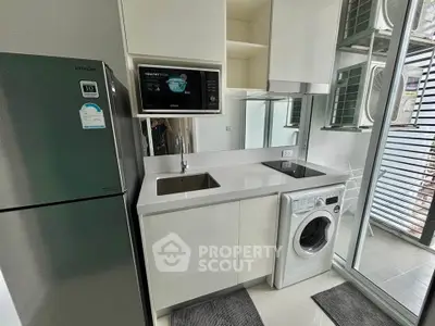 Modern kitchen with sleek appliances and washing machine in compact layout