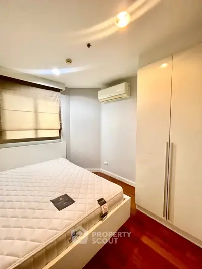 Modern bedroom with sleek wardrobe and air conditioning in a cozy apartment.