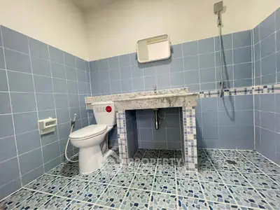 Spacious bathroom with blue tiles and modern fixtures, featuring a sleek shower and elegant marble countertop.