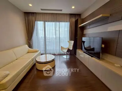 Modern living room with sleek furniture and large window offering city views.