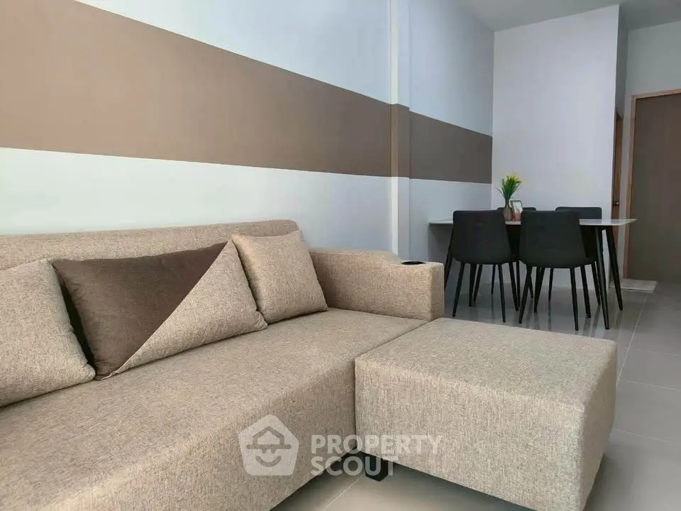 Modern living room with stylish beige sofa and dining area in open layout apartment.