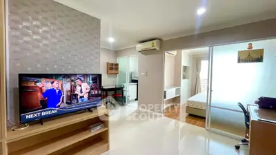 Modern open-plan living room with TV, dining area, and bedroom access in a stylish apartment.
