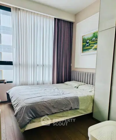 Modern bedroom with large window and stylish decor in a high-rise apartment.