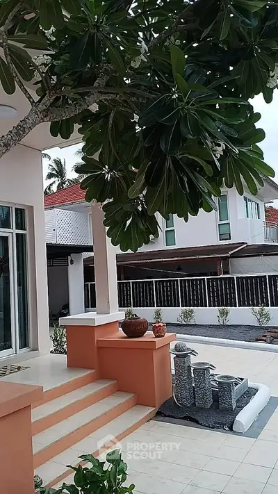 Charming exterior view of a modern home with lush greenery and elegant entrance steps.