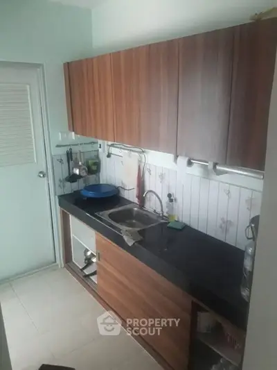 Compact kitchen with wooden cabinets and black countertop