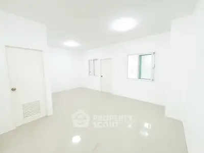 Spacious empty room with white walls and tiled floor, featuring two windows and a door.