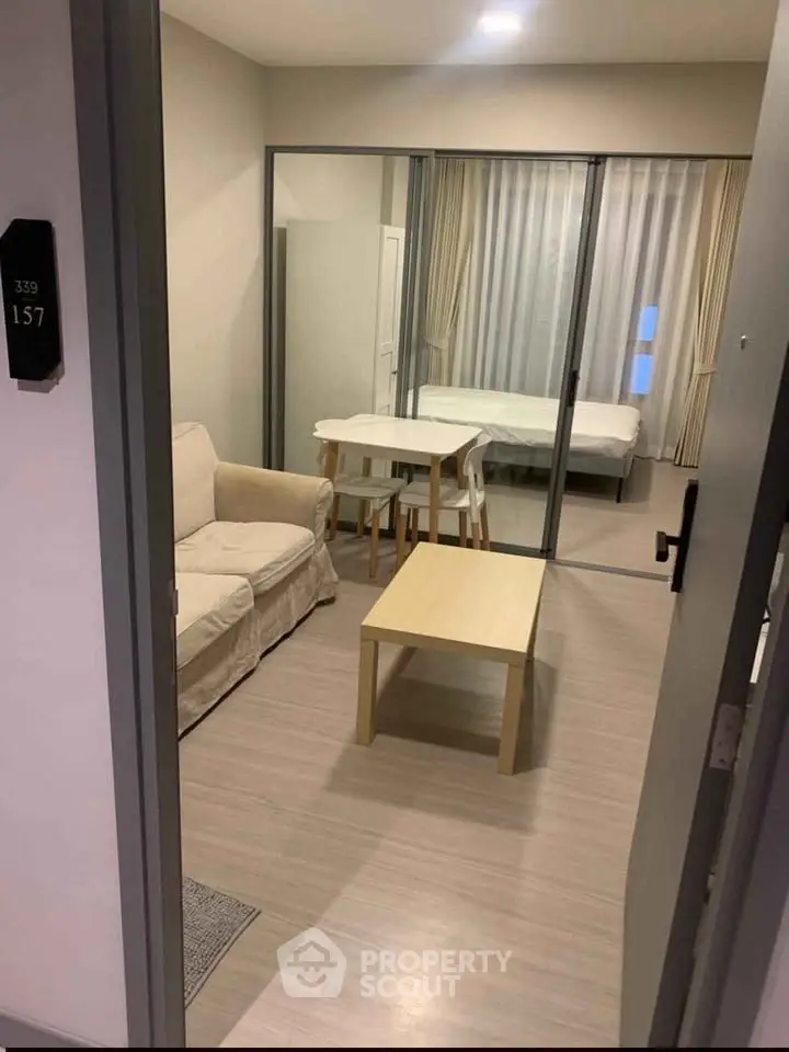 Modern studio apartment with open layout, featuring cozy living area and bedroom separated by glass doors.