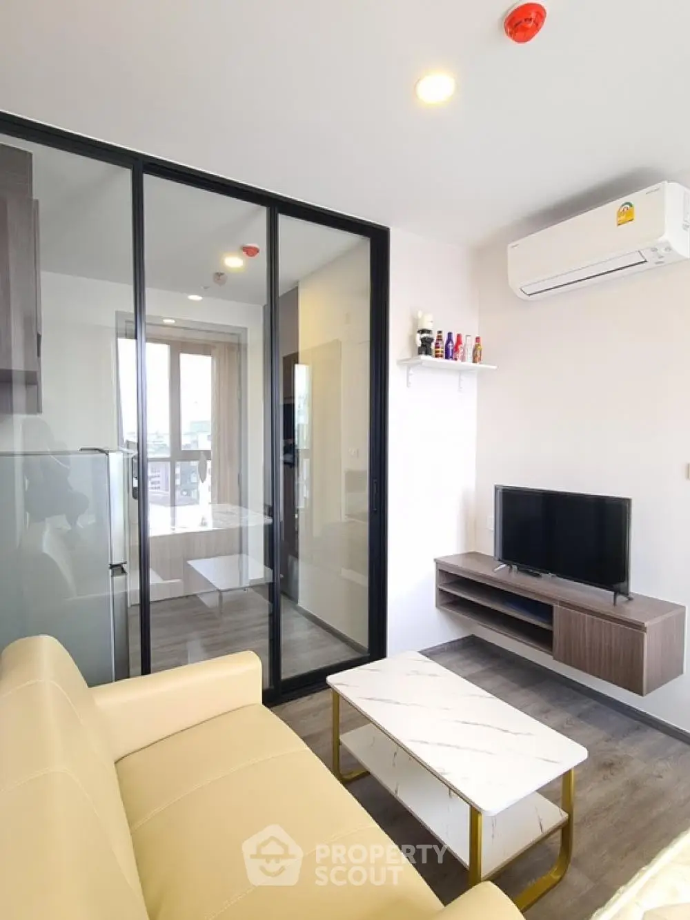 Modern living room with glass partition, cozy sofa, and mounted TV in a stylish apartment.