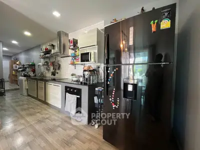 Modern kitchen with sleek black fridge and open shelving in stylish apartment.