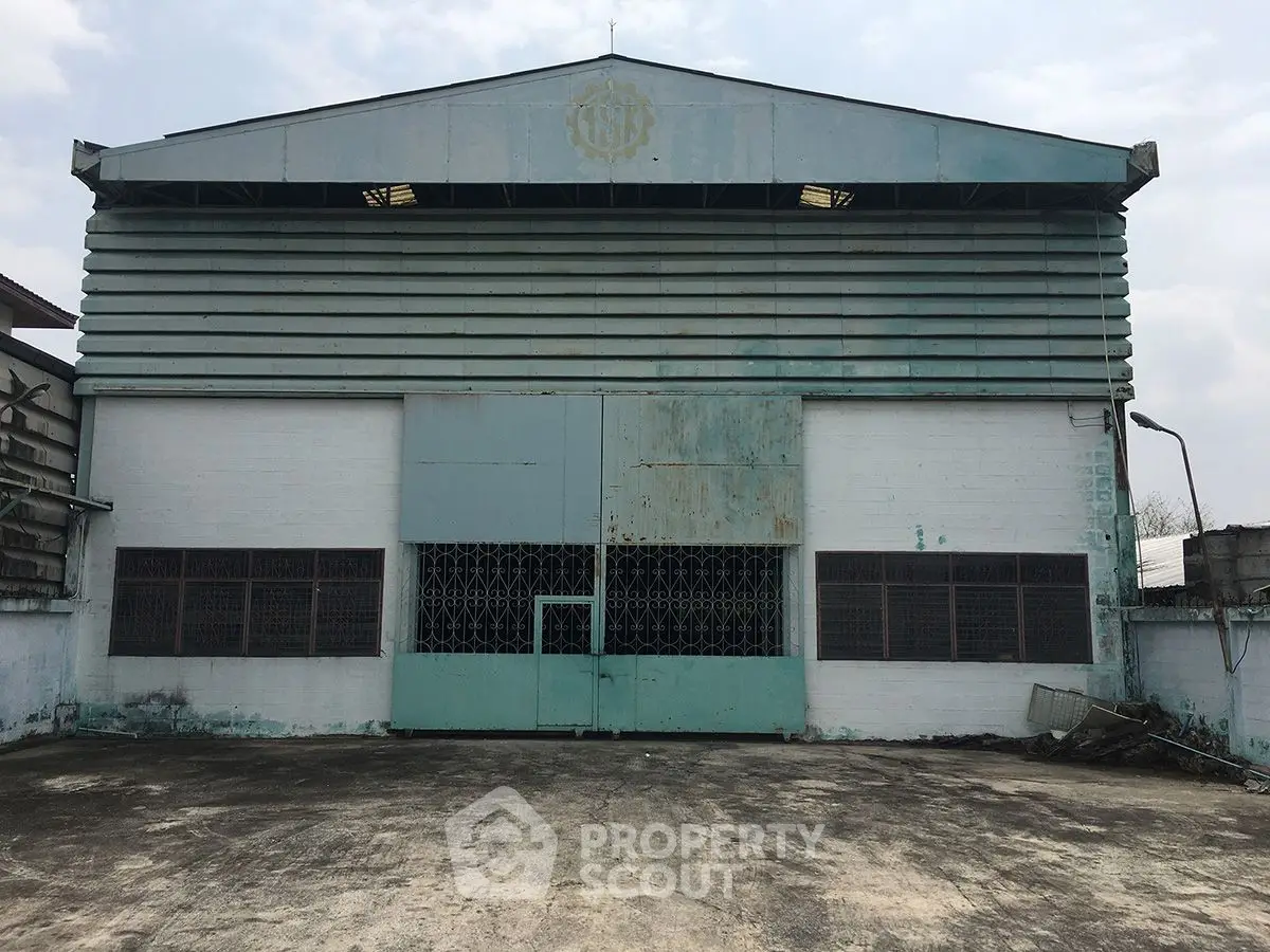 Industrial warehouse exterior with large metal doors and concrete yard