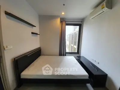 Compact and modern bedroom with a large window allowing natural light, featuring a wall-mounted shelf and an air conditioning unit, perfect for urban living.