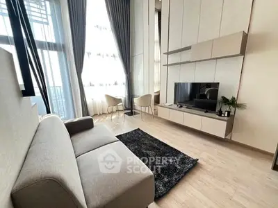 Modern living room with high ceilings and large windows, featuring sleek furniture and a cozy atmosphere.