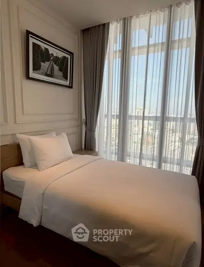 Elegant bedroom with large window and stylish decor, offering a serene city view.