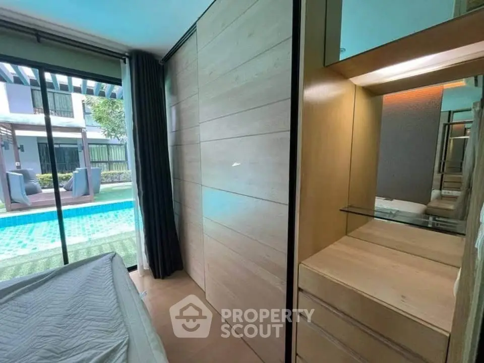 Modern bedroom with pool view and sleek wooden furnishings