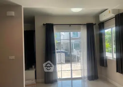 Bright living room with large windows and modern curtains, offering a view of the garden.