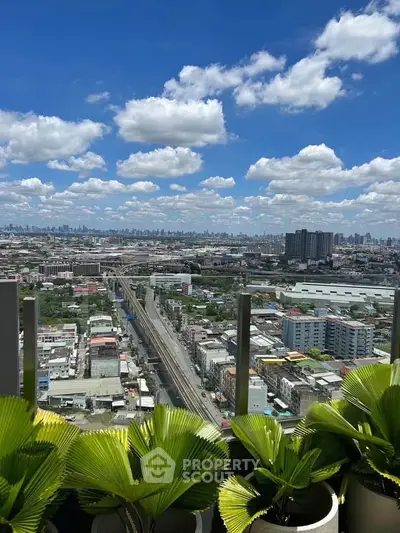 Stunning cityscape view from a high-rise balcony with lush greenery and clear blue skies.