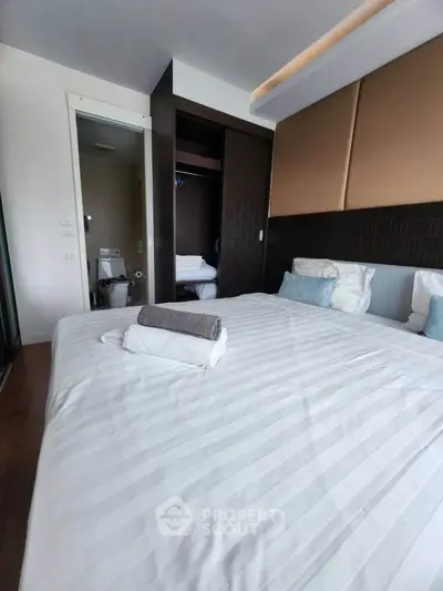 Modern bedroom with elegant design and ensuite bathroom, featuring cozy bedding and stylish decor.