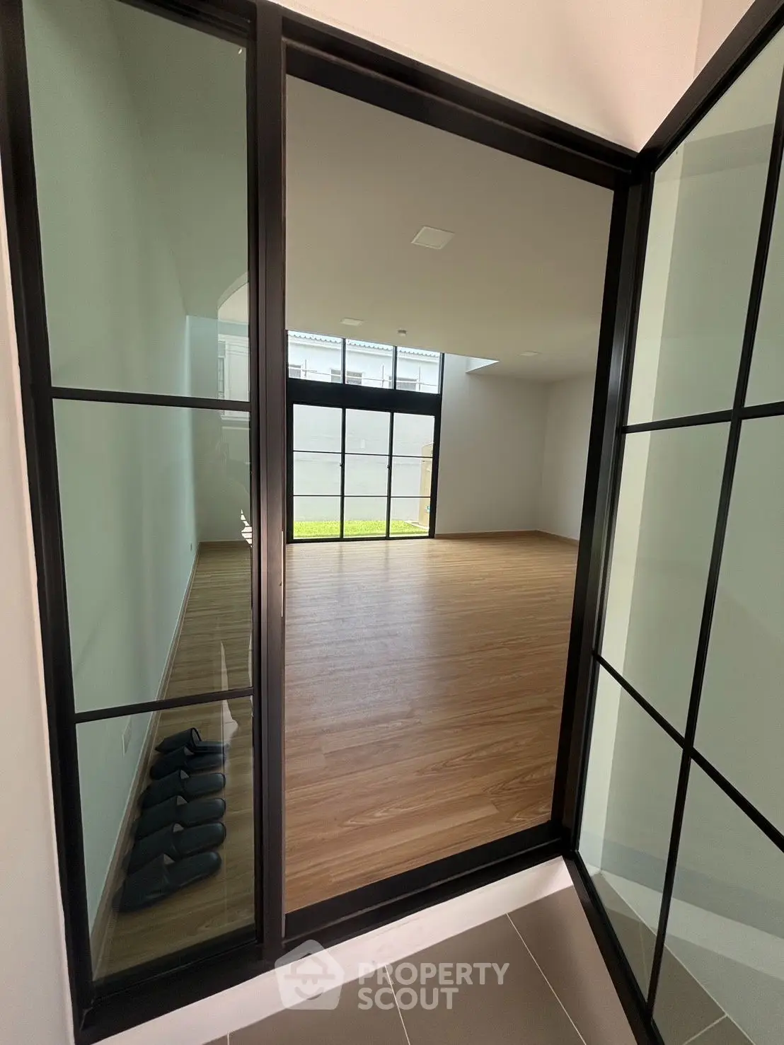 Spacious modern room with large windows and sleek wooden flooring, perfect for versatile living space.