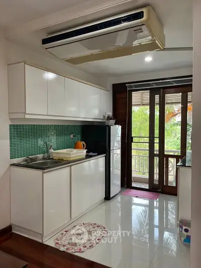 Charming kitchen with balcony view, featuring sleek cabinetry and modern appliances.