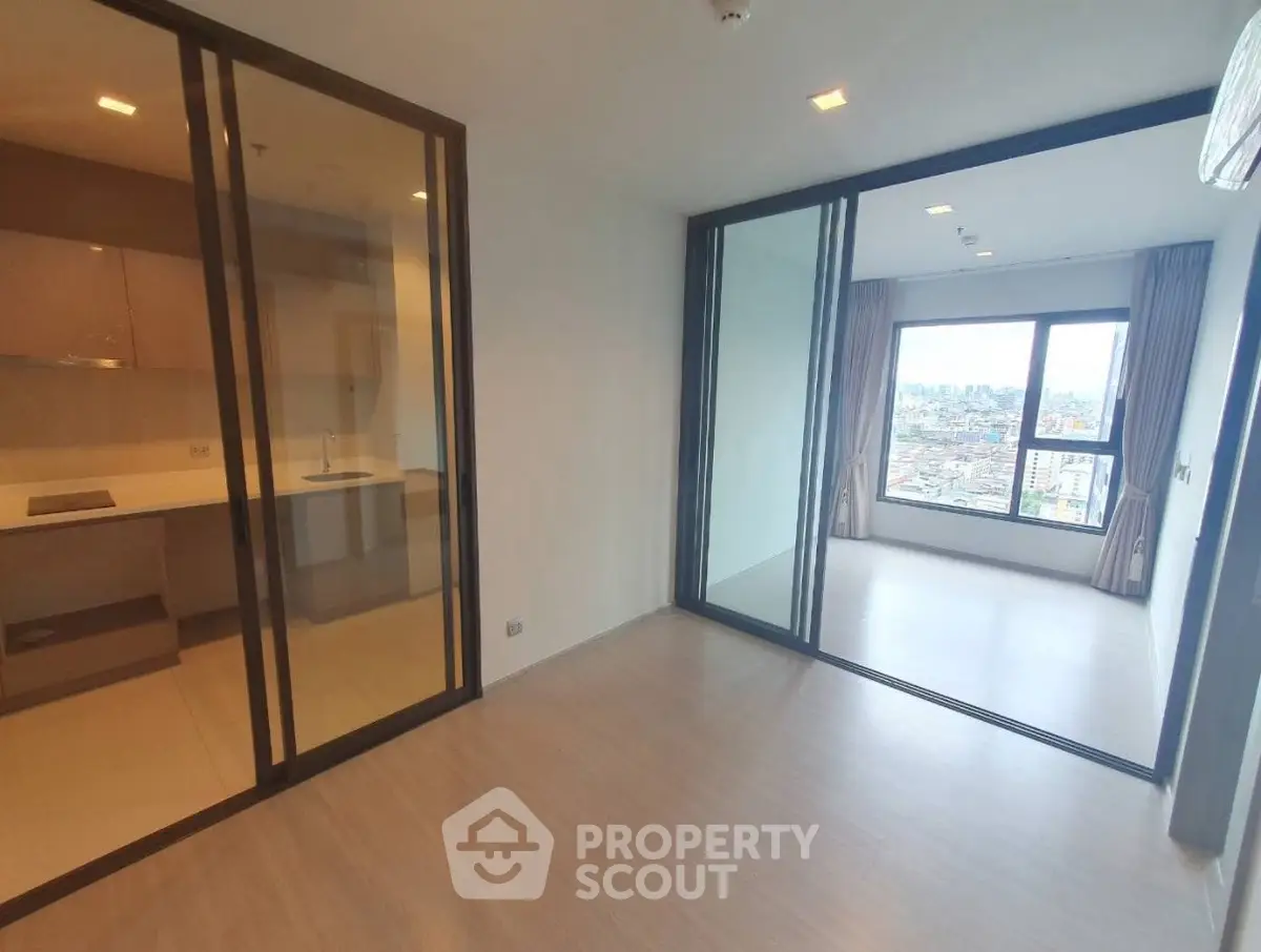 Modern apartment with open layout and city view, featuring glass partitions and sleek kitchen design.