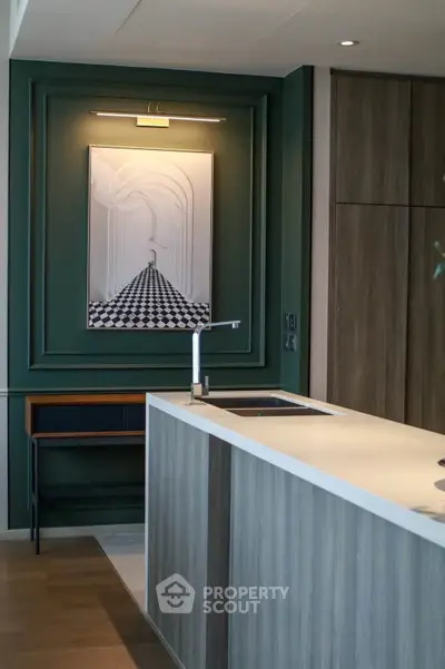Modern kitchen with sleek design and stylish artwork, featuring a minimalist island and elegant cabinetry.