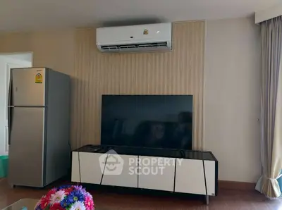 Modern living room with sleek TV stand, air conditioning, and refrigerator, perfect for comfortable living.