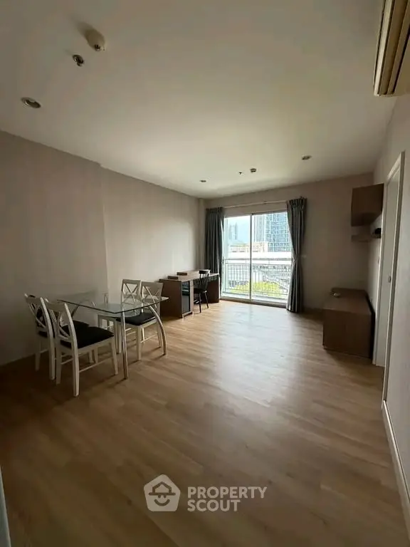 Spacious living room with wooden flooring and city view balcony in modern apartment.
