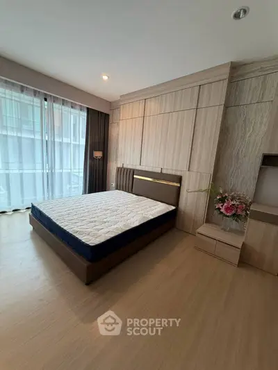 Spacious modern bedroom with elegant wood paneling and large window for natural light.