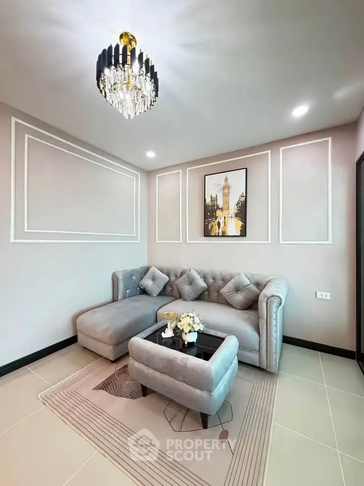 Elegant living room with plush gray sofa, chic chandelier, and modern decor accents.